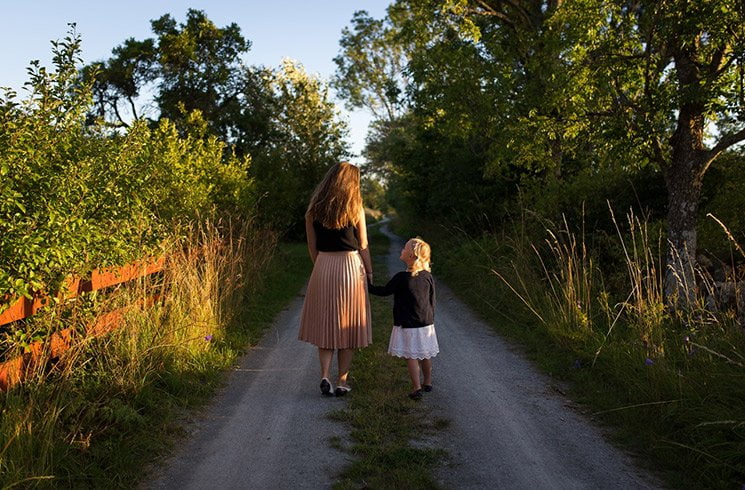 Une mère accompagne son enfant sur un chemin de campagne.